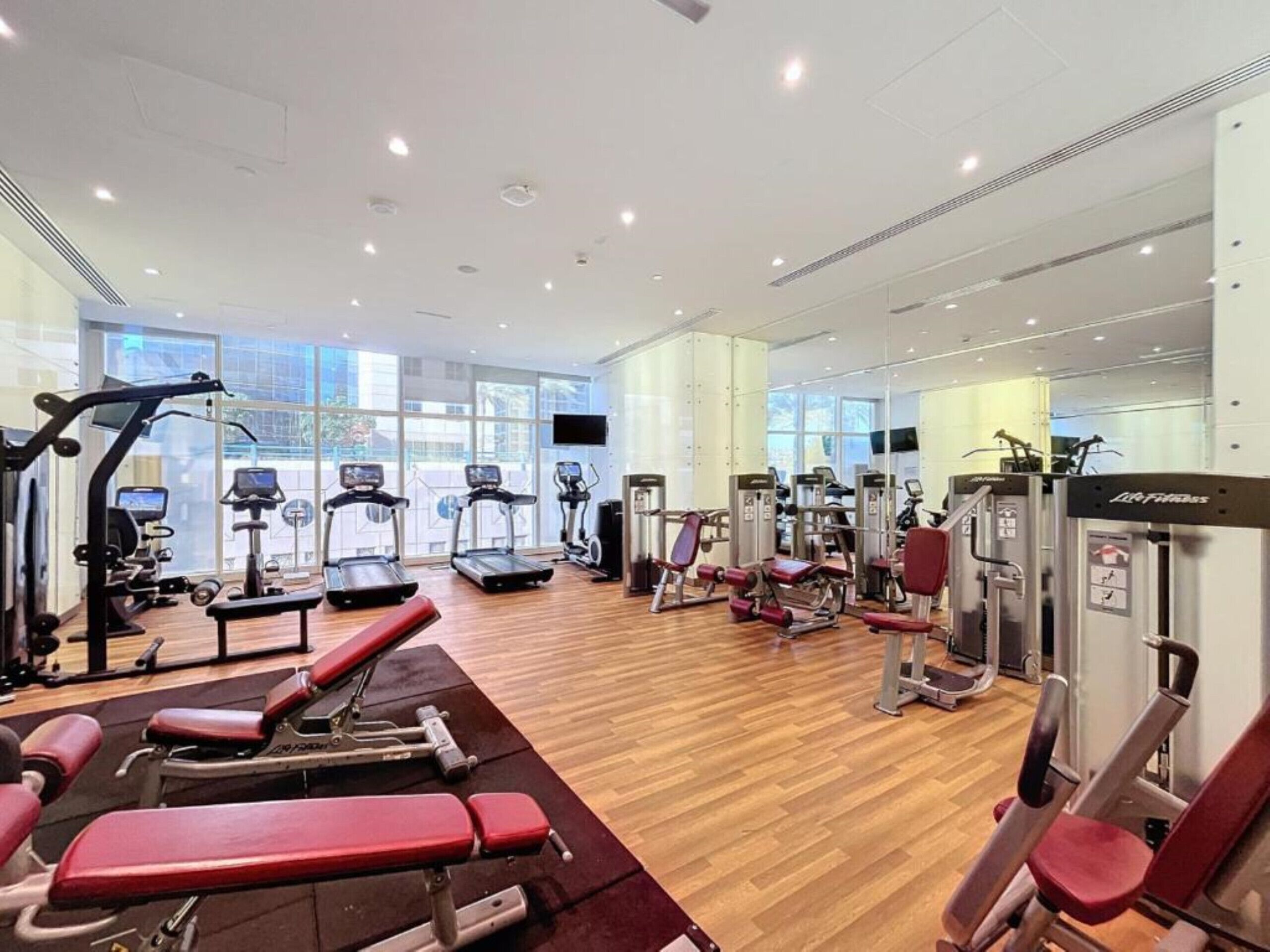 Une salle de sport équipée de tapis de course, d’appareils de musculation et de bancs.