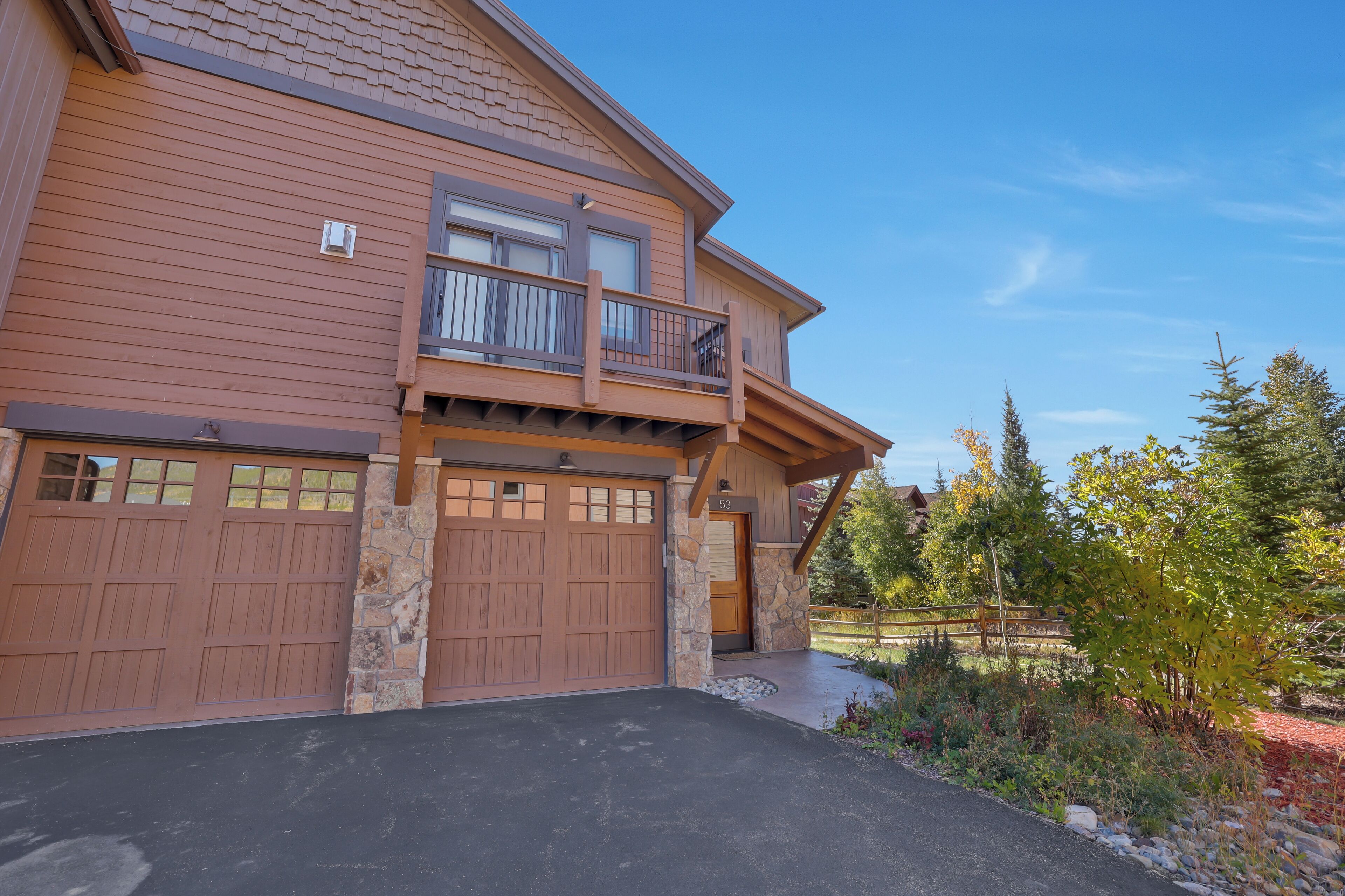 A two-story house with a stone foundation, a balcony, and a garage.