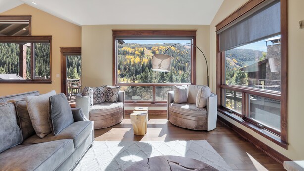 A spacious living room with a large window offering a scenic view of a forested area. - Charming Mountain Getaway in Keystone, CO (Keystone)
