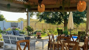An outdoor patio with wooden furniture, a pool, and lush greenery. - Sun Valley Farm Guest House (Chegutu)