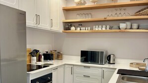A modern kitchen with white cabinets, a stainless steel refrigerator, a microwave, and a double sink. - Sun Valley Farm Guest House (Chegutu)