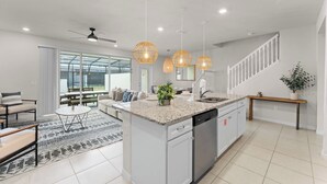 A modern kitchen with a central island, pendant lighting, and a view to the outside. - Relax in Style with Private Pool, BBQ and More (Davenport)