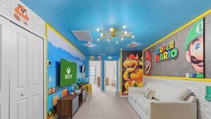 A room with a blue ceiling, a white couch, a TV, and Mario-themed decorations. - Relax in Style with Private Pool, BBQ and More (Davenport)