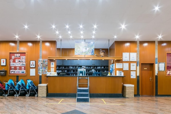 A reception area with a wooden counter, framed photos, and a ladder leading to a higher level.