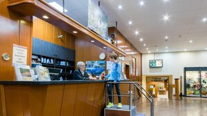A reception area with a wooden counter, a clock, and a digital screen displaying information.