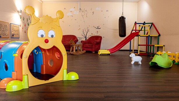 A playroom with a colorful playhouse, a slide, and a climbing structure.