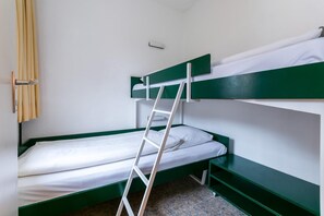 Ein Schlafraum mit Etagenbetten, einer Leiter, weißer Bettwäsche und grünen Akzenten.