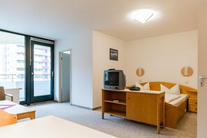 Ein Hotelzimmer mit Bett, Schreibtisch mit Fernseher, Stuhl und Fenster mit Blick auf Gebäude.