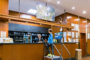 A reception area with a wooden counter, a clock, and informational posters. - Appartement im Panoramic Hotel Bad Lauterberg (Bad Lauterberg)