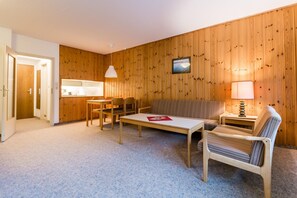 A cozy room with a wooden wall, a sofa, a table, and a chair.