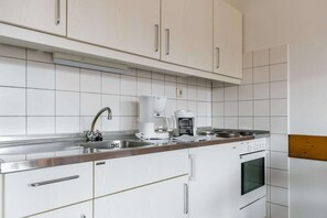 Eine moderne Küche mit weißen Schränken, Edelstahlgeräten und einem eingebauten Backofen.