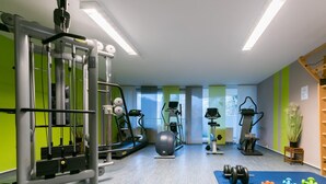 Ein Fitnessstudio mit verschiedenen Trainingsgeräten, darunter Laufband, Crosstrainer und Kraftgeräte.
