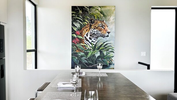 Ett konferensrum med ett långt bord, två vinglas och en tavla med en leopard på väggen.