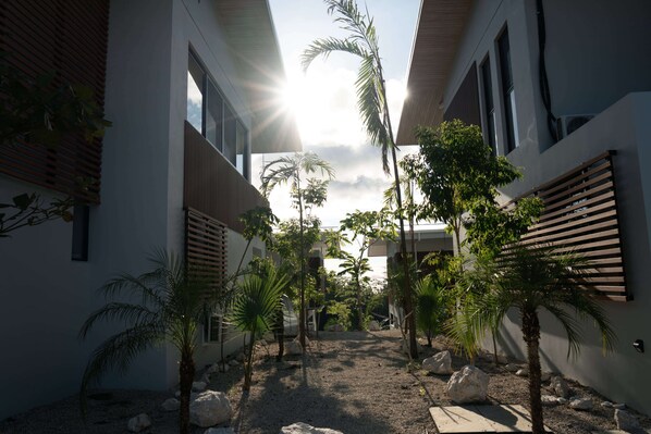 A modern building with a central courtyard surrounded by palm trees and large rocks. - Solindo Stays (Cuajiniquil)