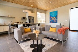 A modern living space with a grey sofa, a round coffee table, and a painting of a turtle on the wall. - Solindo Stays (Cuajiniquil)