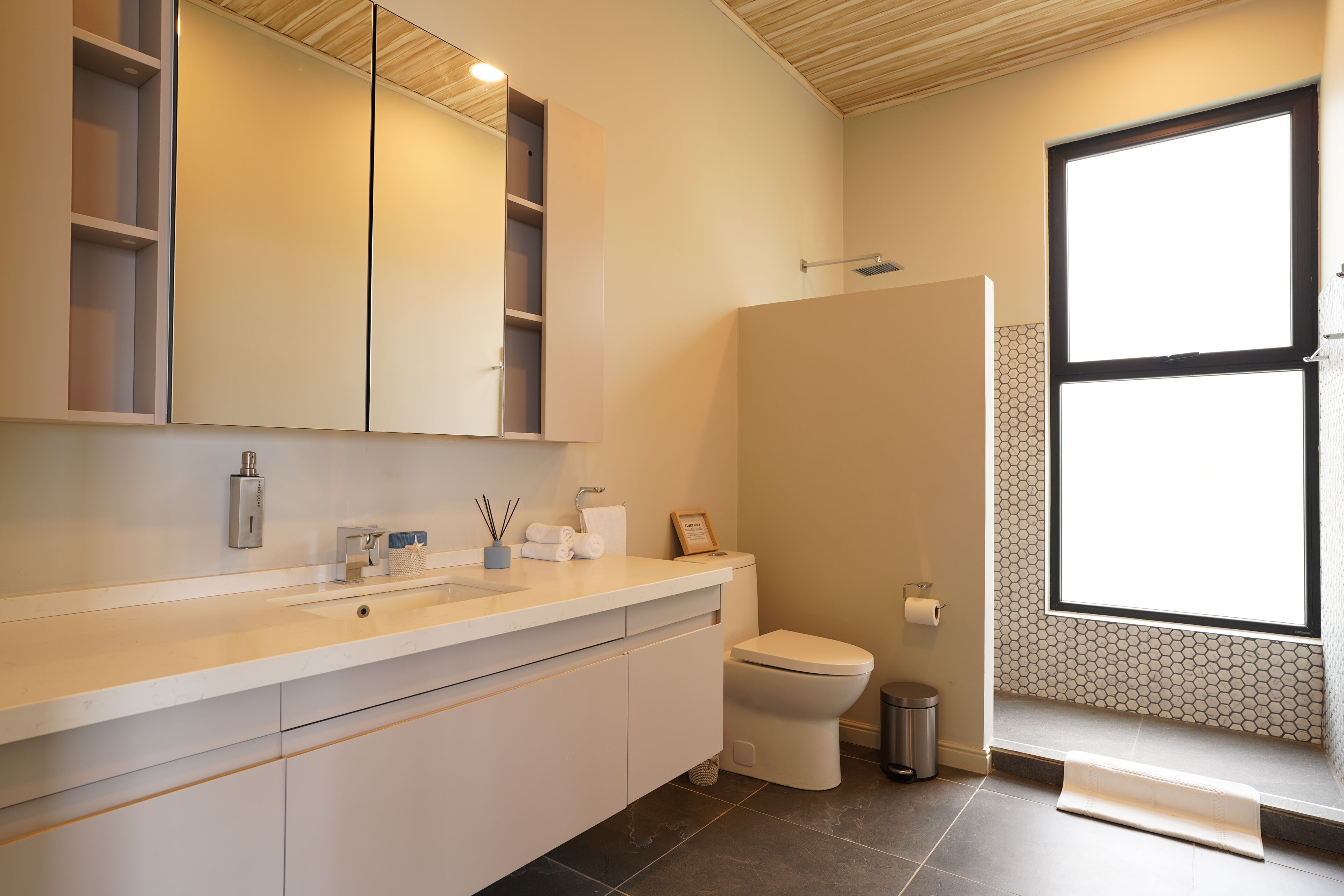 A modern bathroom with a large mirror, a toilet, and a sink.