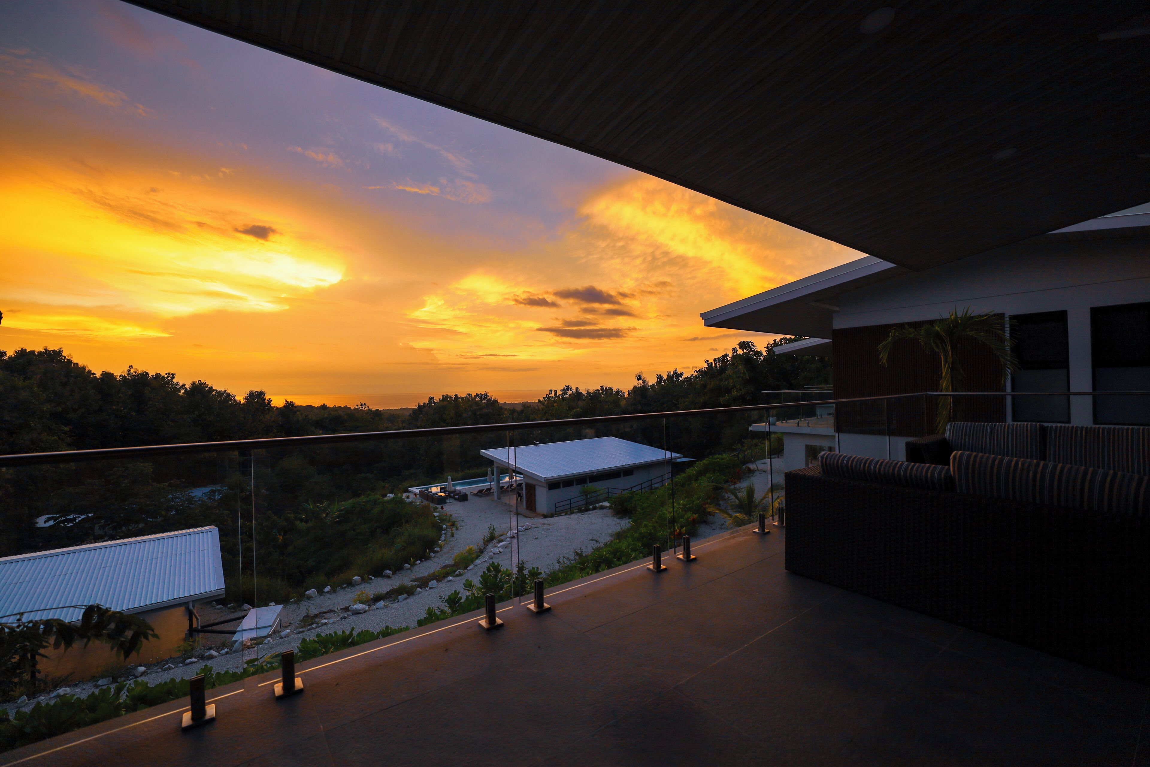 A modern building with a rooftop terrace overlooking a sunset.