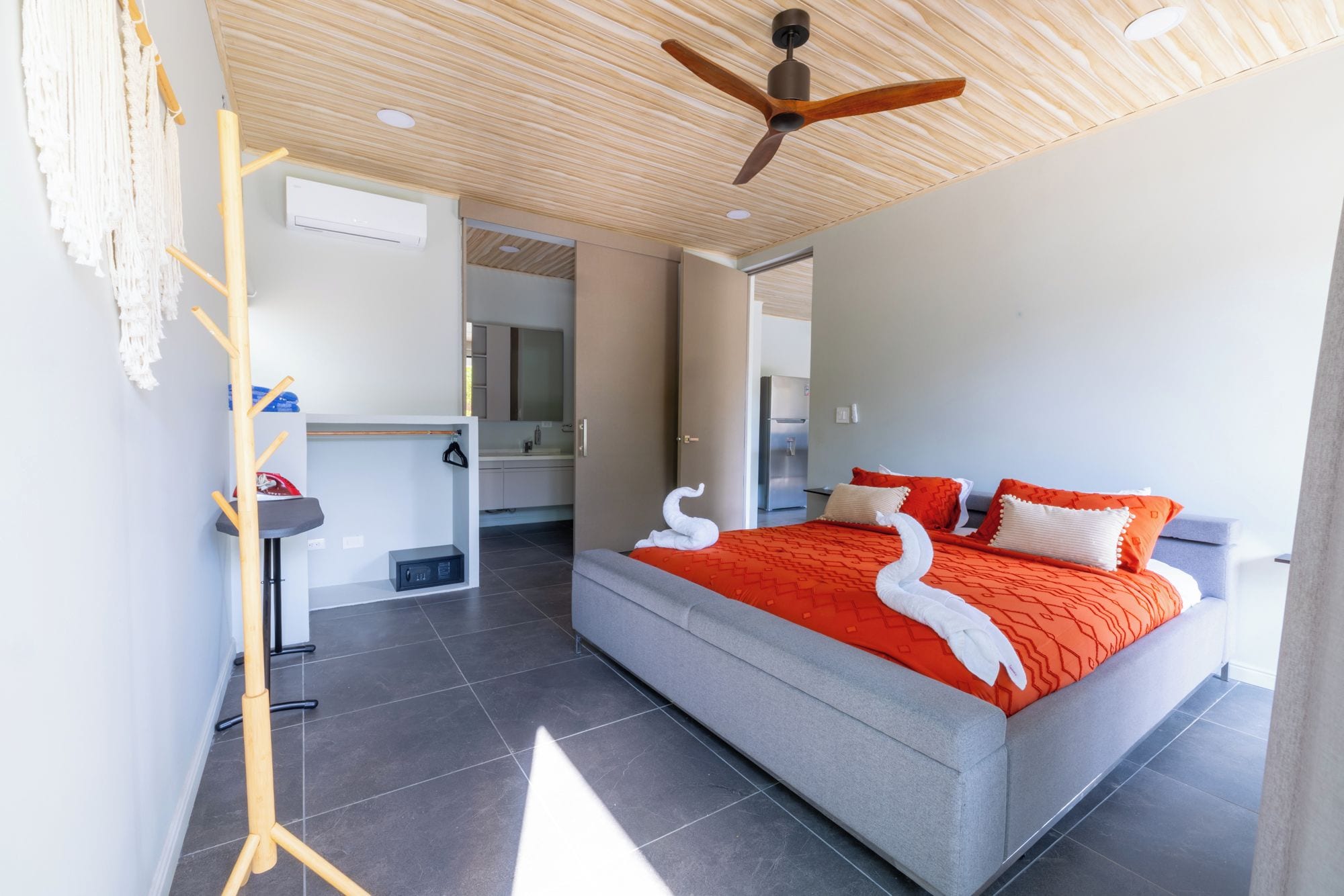 Habitación de hotel moderna con una cama grande, un ventilador de techo y vistas a la cocina.