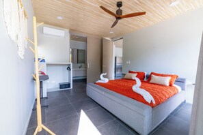 A modern hotel room with a large bed, a ceiling fan, and a view of the kitchen. - Solindo Stays (Cuajiniquil)