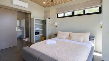 A bedroom with a large bed, a walk-in closet, a window with blinds, and a ceiling fan.