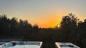 Två bubbelpooler med utsikt över solnedgången och den omgivande skogen.
