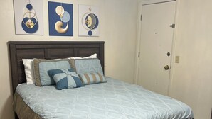Un dormitorio con cama, ventilador de techo y cuadros en la pared.