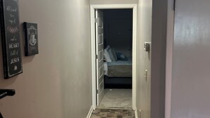 Un estrecho pasillo con suelo de baldosas que conduce a un dormitorio.