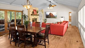 A spacious living area with a dining table, red sofa, and a fireplace. - NEW! Peaceful Sedona Gem (Sedona)