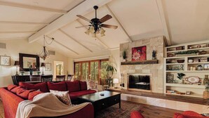 A spacious living room with a red sofa, a fireplace, and a television. - NEW! Peaceful Sedona Gem (Sedona)