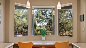 A kitchen with a central island, two chairs, and large windows with a view of trees. - NEW! Peaceful Sedona Gem (Sedona)