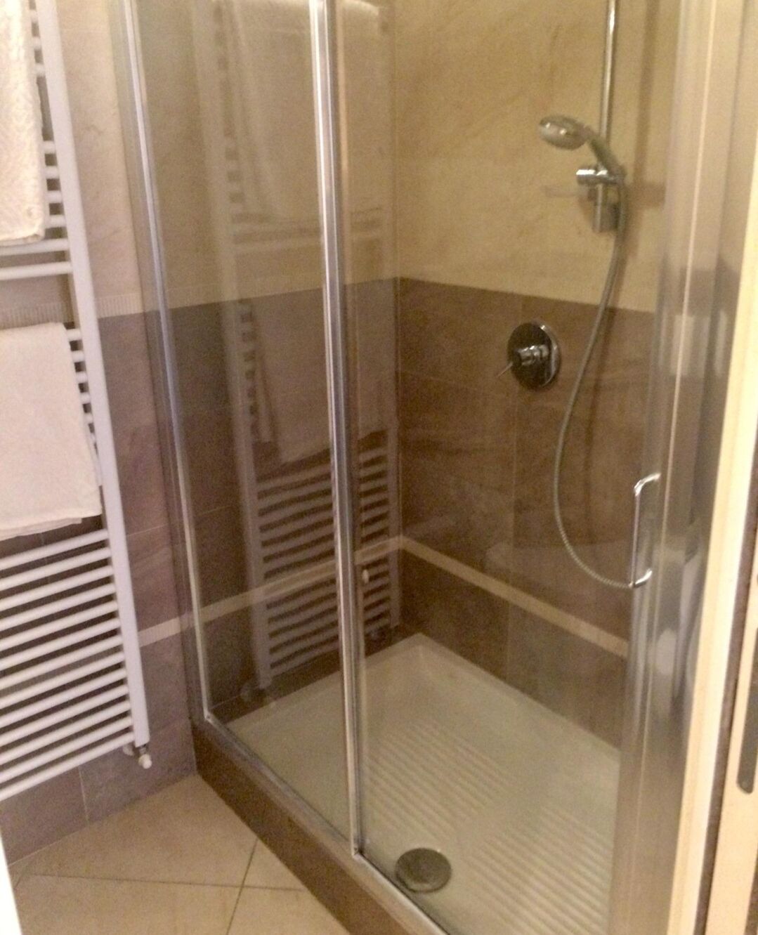 Une douche fermée par des parois en verre, dotée d’un panneau de commande et d’un porte-serviettes.