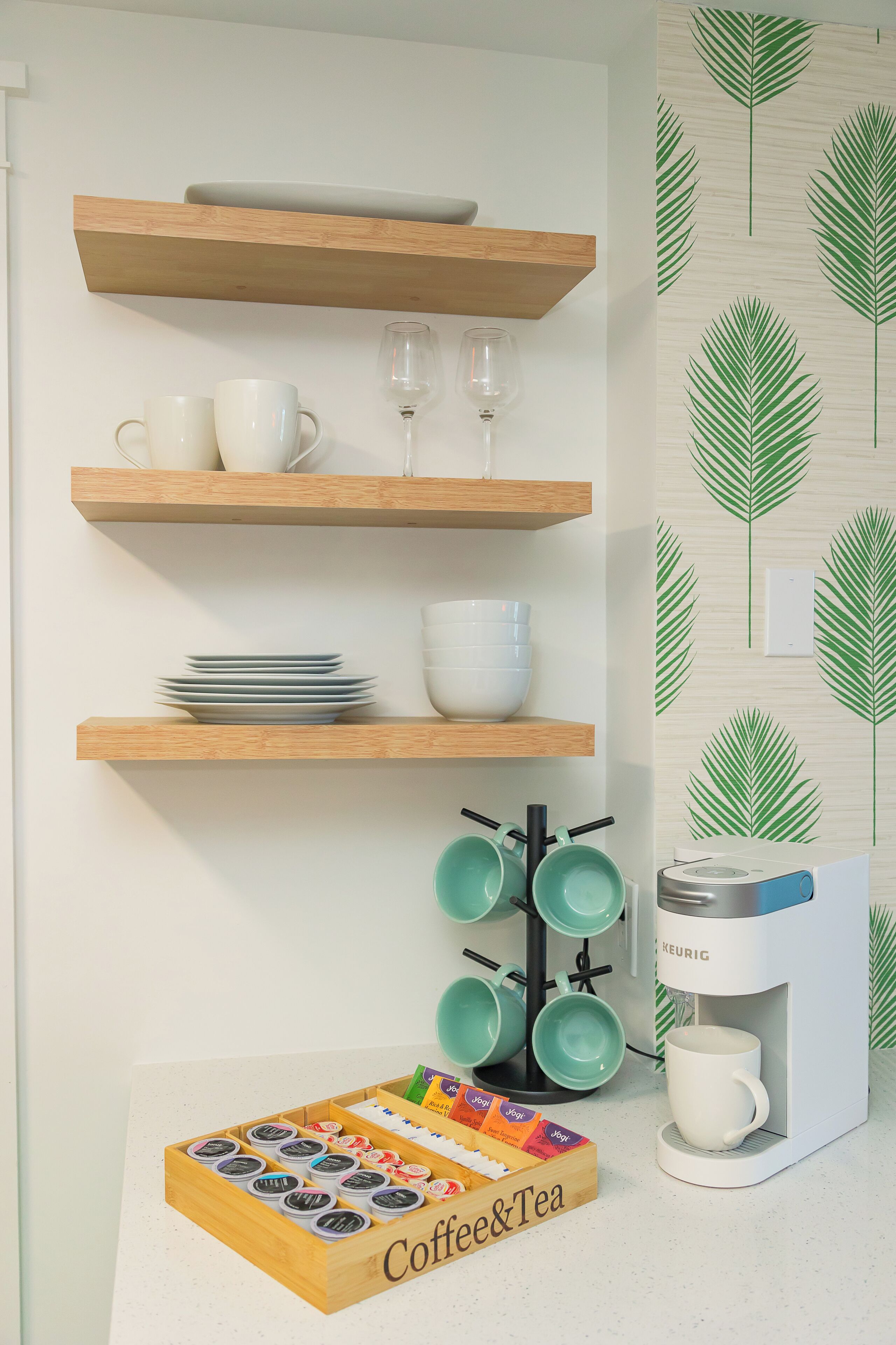 Una cocina con repisas de madera que sostienen tazas, recipientes y una cafetera.