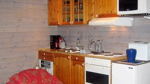 Eine kleine Küche mit Holzschränken, einer Mikrowelle, einem Herd und einem Spülbecken.