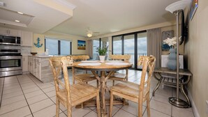A spacious kitchen with a dining area, large windows, and a view of the ocean.