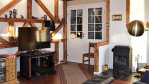 A cozy living room with a TV, wooden beams, a fireplace, and a comfortable seating area. - 5 Person Holiday Home in Laukvik-by Traum (Vagan)