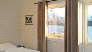 A bedroom with a bed, a window with curtains, and a framed picture on the wall. - 5 Person Holiday Home in Laukvik-by Traum (Vagan)
