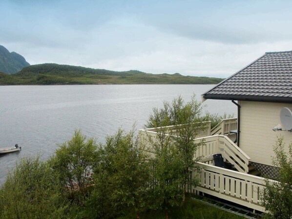 A lakeside cabin with a balcony overlooking the water, surrounded by greenery. - 5 Person Holiday Home in Laukvik-by Traum (Vagan)