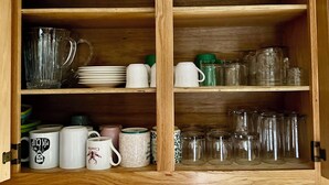 Puisesta valmistettu keittiökaappi, jossa on hyllyjä lasiesineille, lautasille ja mukeille.