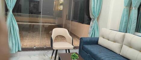Un salón moderno con un sofá azul, un sillón beige y una pequeña mesa con una planta.