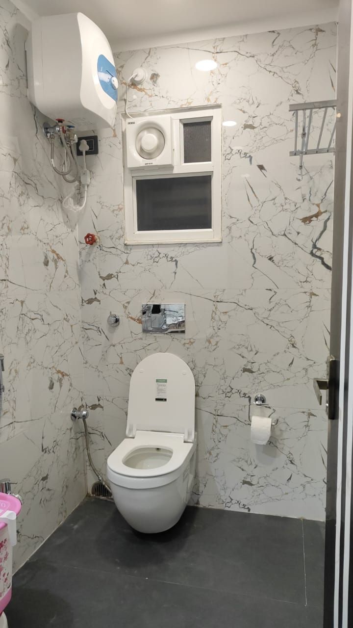 A bathroom with a toilet, a shower, and a wall-mounted air conditioning unit.