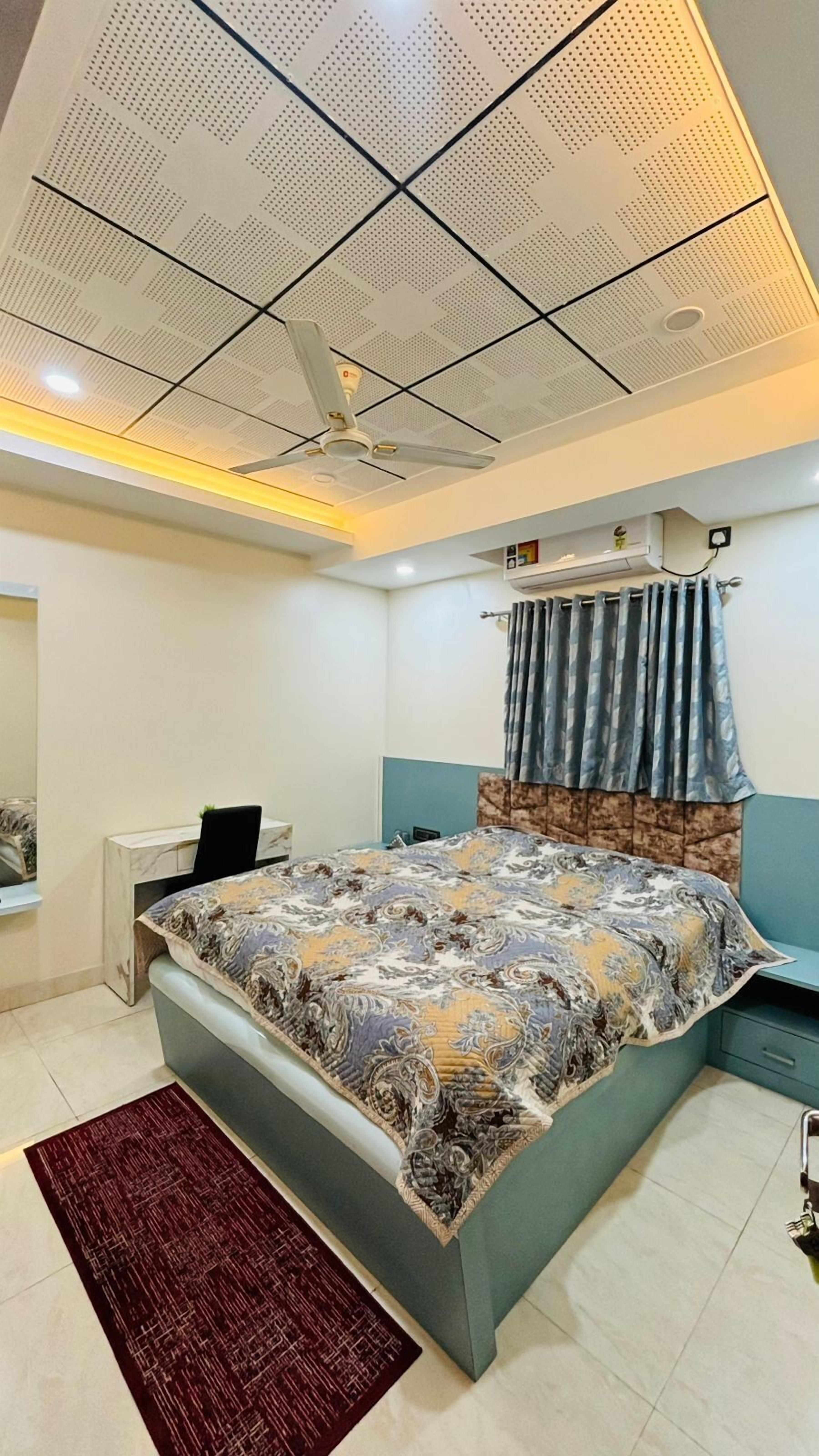 A bedroom with a bed, a desk, and a ceiling fan.