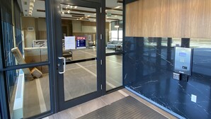 Un hall d’hôtel moderne avec une entrée dotée d’une porte en verre, un comptoir d’accueil, un kiosque d’enregistrement numérique et un lustre.