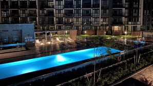 Un bâtiment moderne doté de nombreux balcons et d’un espace piscine avec des chaises longues.