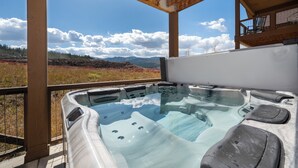 Ein Whirlpool mit freiem Blick auf Berge und einer Holzterrasse.