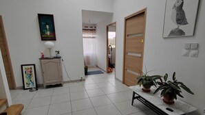 Une pièce spacieuse avec une lucarne, une porte en bois, une armoire blanche, un tableau encadré et une plante en pot.