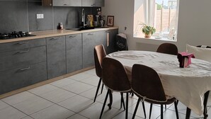 Une cuisine moderne avec des meubles gris, un plan de travail noir et un coin repas comprenant une table ronde et des chaises.