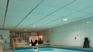 An indoor swimming pool with tiled walls and a tiled floor.