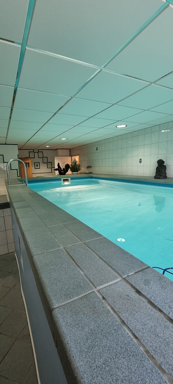 An indoor swimming pool with tiled walls and a tiled floor.