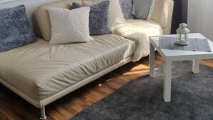 A modern living room with a beige sofa, a white coffee table, and a grey rug.
