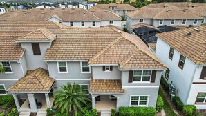 A residential area with multiple two-story houses featuring tiled roofs and white exteriors. - 5BR Townhouse Near Disney Pool (Kissimmee)